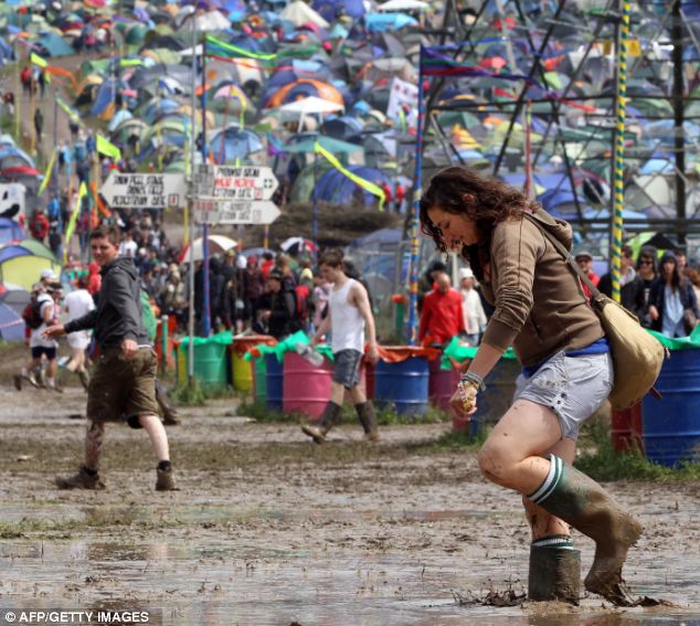 Quagmire: A festival-goer carefully walks through a puddle at the Glastonbury festival in Somerset today
