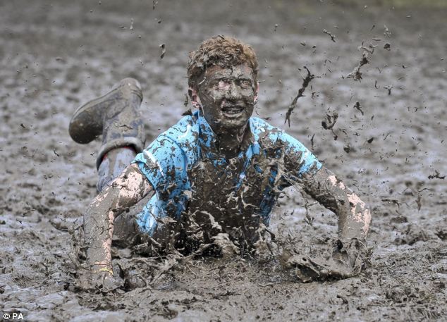 In for a penny... Tom Wilder, 17, from Kent, gets into the festival spirit and performs a dramatic slide in the Glastonbury Festival mud